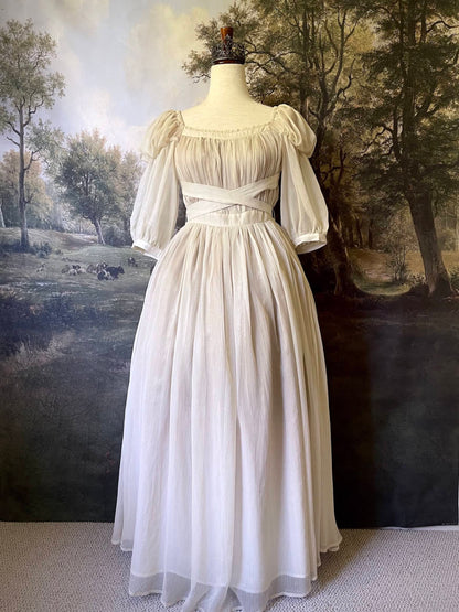 A Historically Inspired Renaissance to Victorian era Pleated Gauzy Chiffon Gown in Ivory, pictured on a mannequin in front of an art history backdrop.