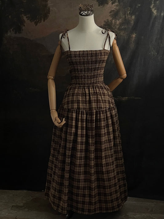 Mannequin wearing a historical fashion inspired brown tartan plaid maxi dress against a dark art history background