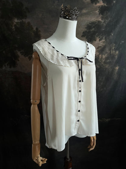 off-white vintage style peter-pan collar blouse with black ribbon bow details on a mannequin against a dark art history background