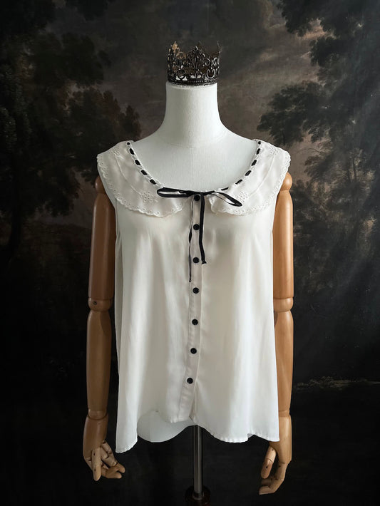 off-white vintage style peter-pan collar blouse with black ribbon bow details on a mannequin against a dark art history background