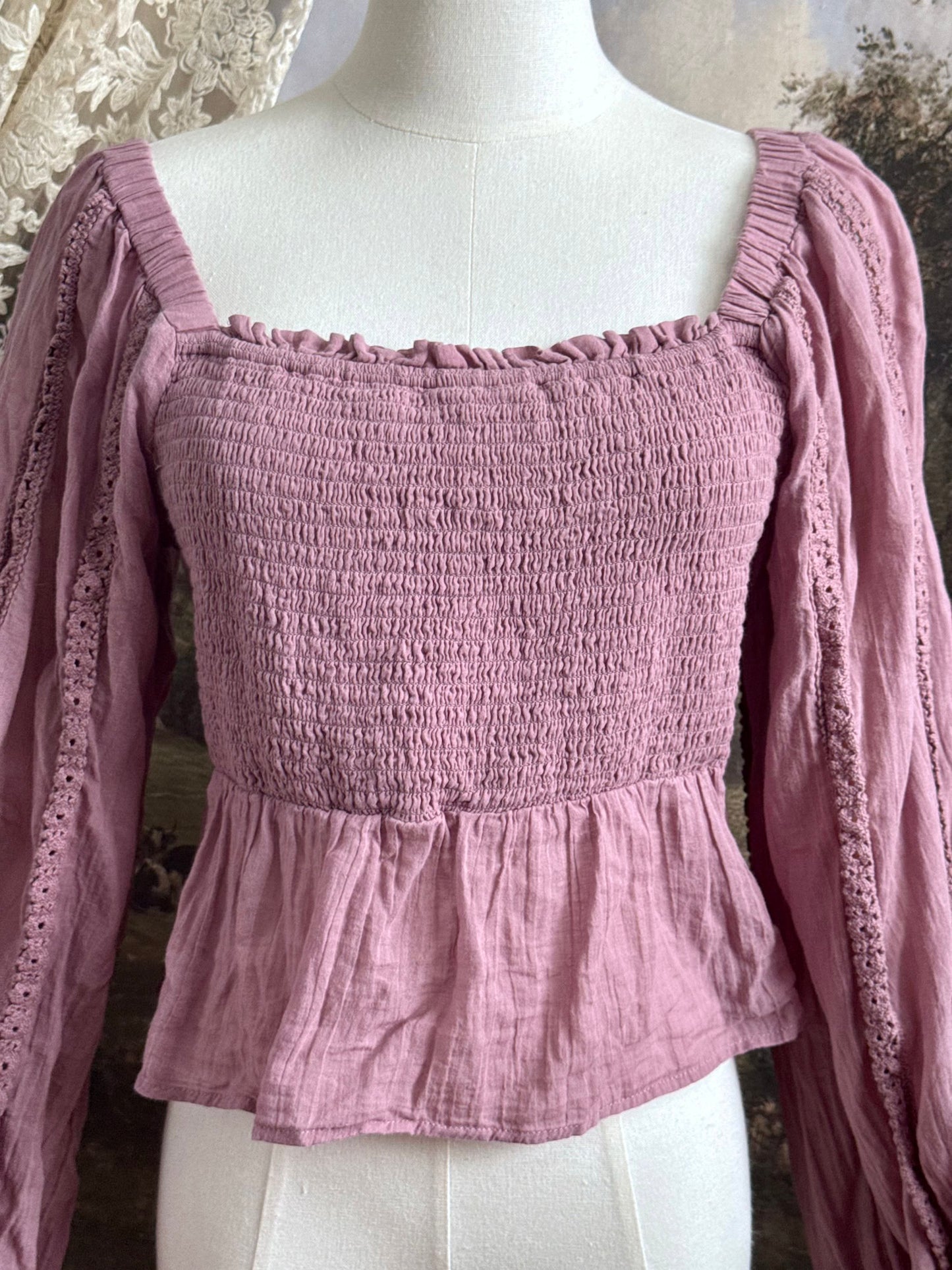 A historically inspired mauve pink shirred cotton peasant blouse with long bishop sleeves pictured on a mannequin