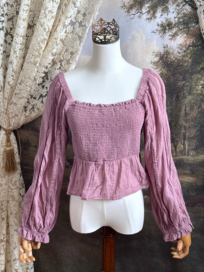 A historically inspired mauve pink shirred cotton peasant blouse with long bishop sleeves pictured on a mannequin