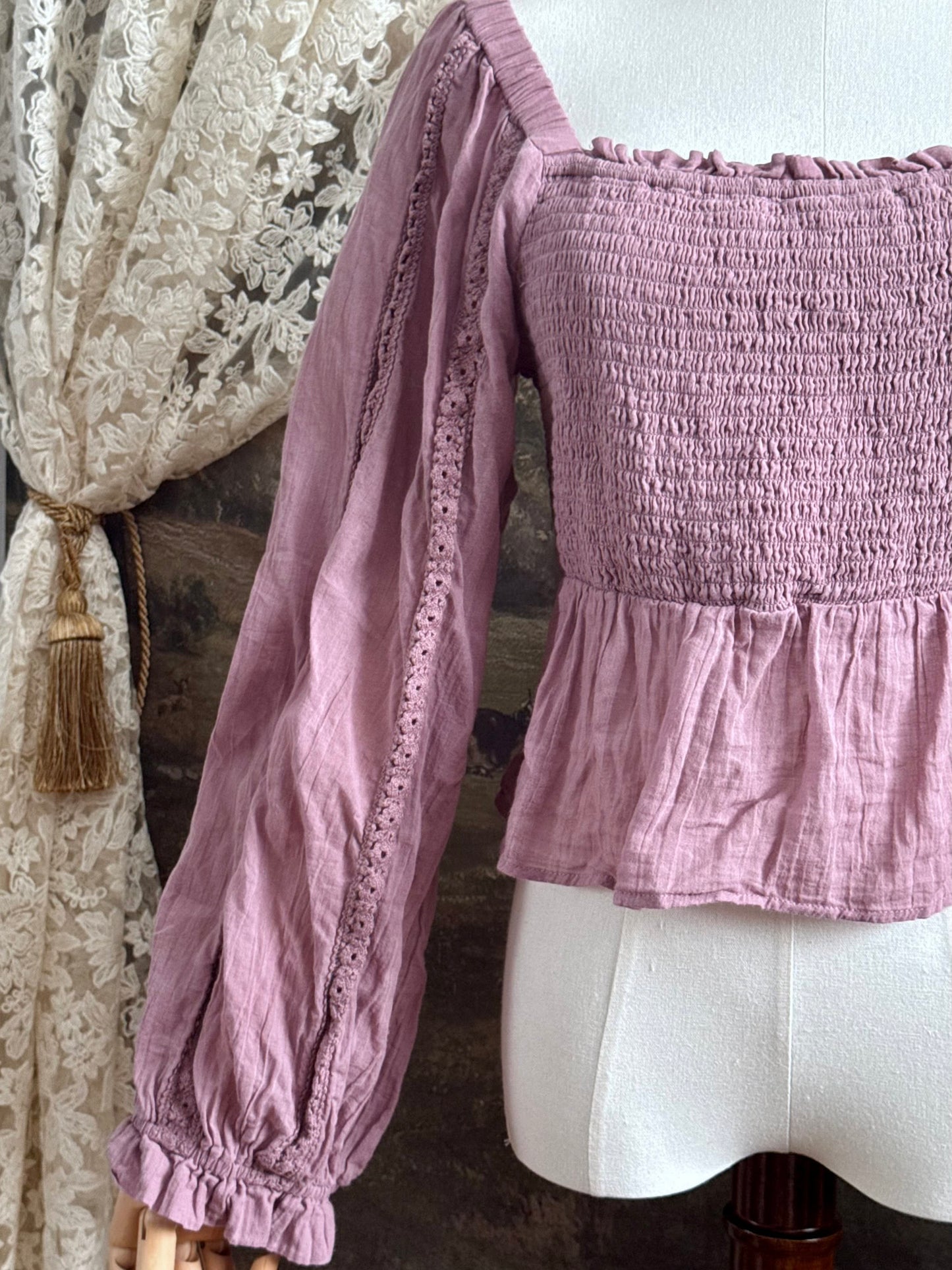 A historically inspired mauve pink shirred cotton peasant blouse with long bishop sleeves pictured on a mannequin
