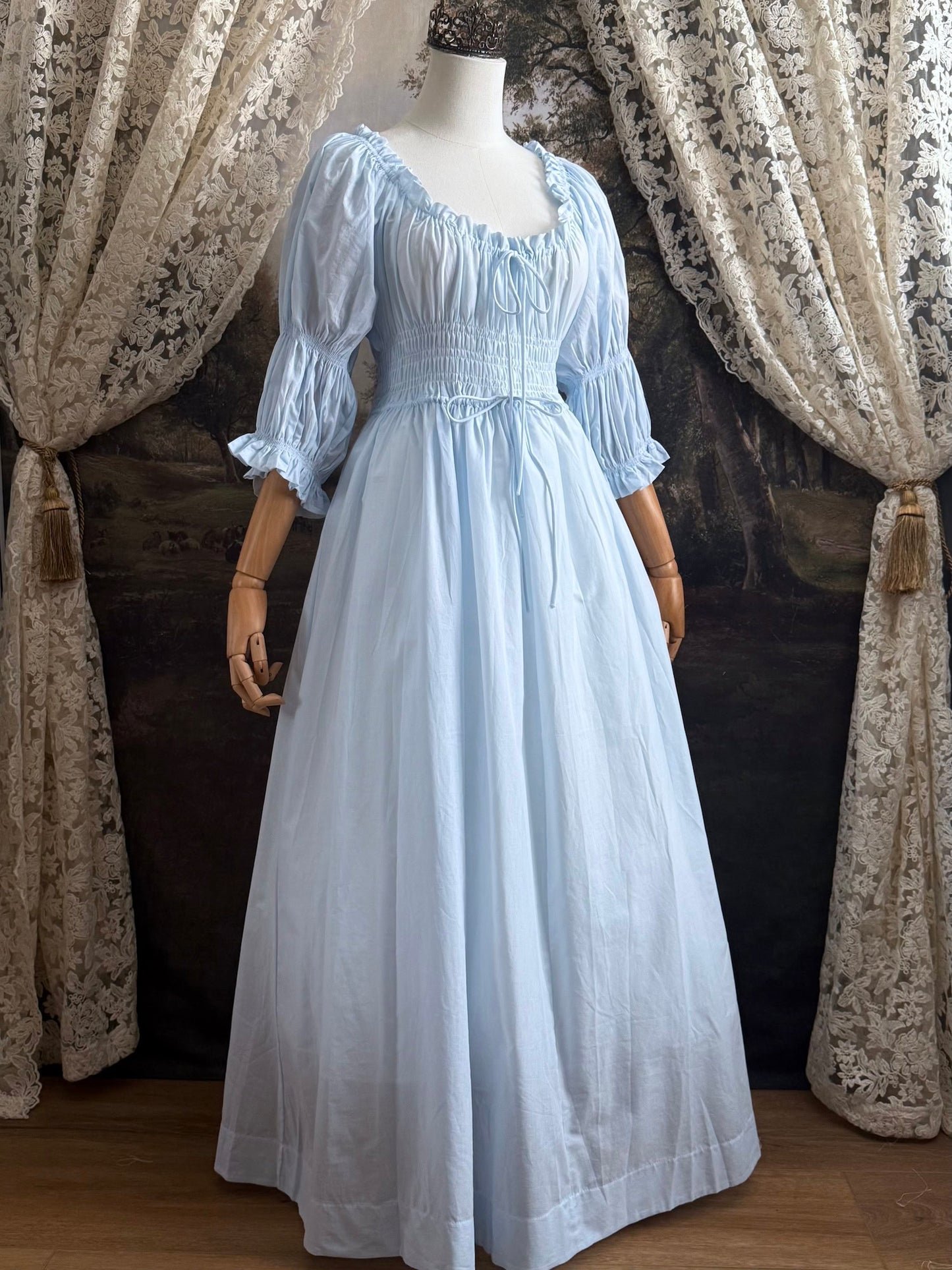 A historically-inspired vintage style light blue shirred / smocked cotton maxi chemise dress with half length virago puff sleeves, pictured on a mannequin
