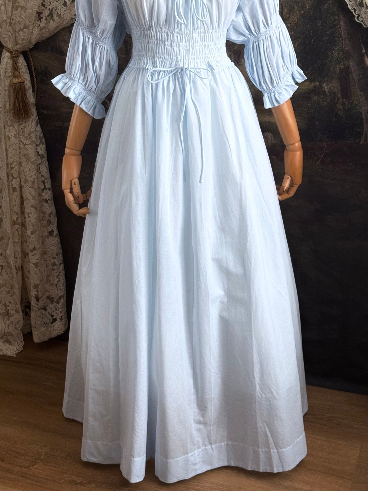 A historically-inspired vintage style light blue shirred / smocked cotton maxi chemise dress with half length virago puff sleeves, pictured on a mannequin