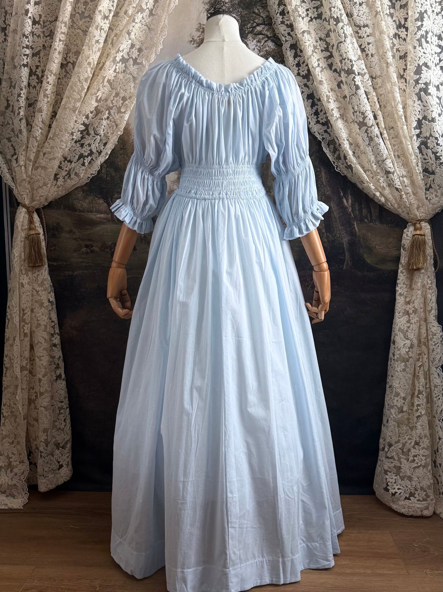 A historically-inspired vintage style light blue shirred / smocked cotton maxi chemise dress with half length virago puff sleeves, pictured on a mannequin