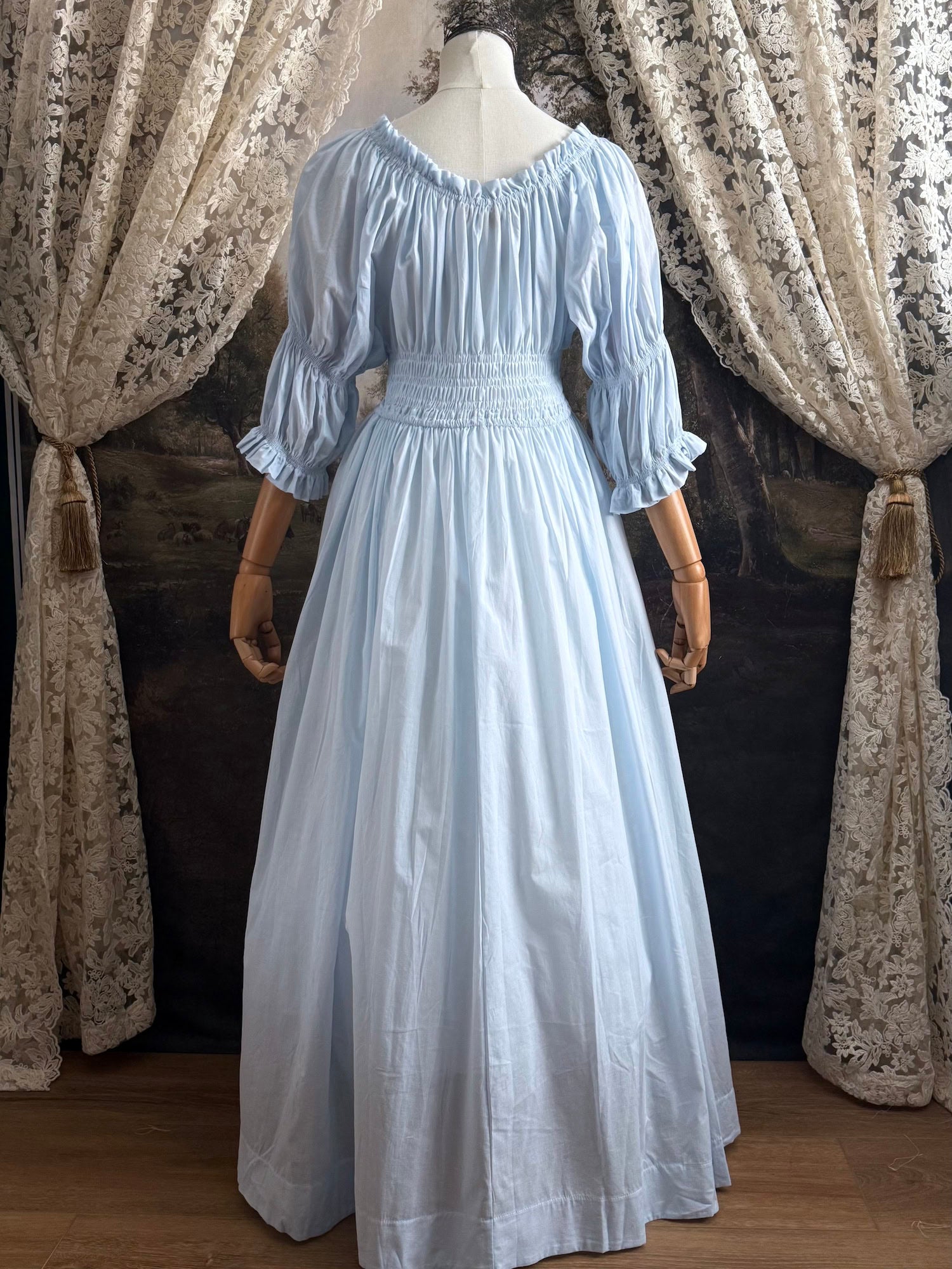 A historically-inspired vintage style light blue shirred / smocked cotton maxi chemise dress with half length virago puff sleeves, pictured on a mannequin