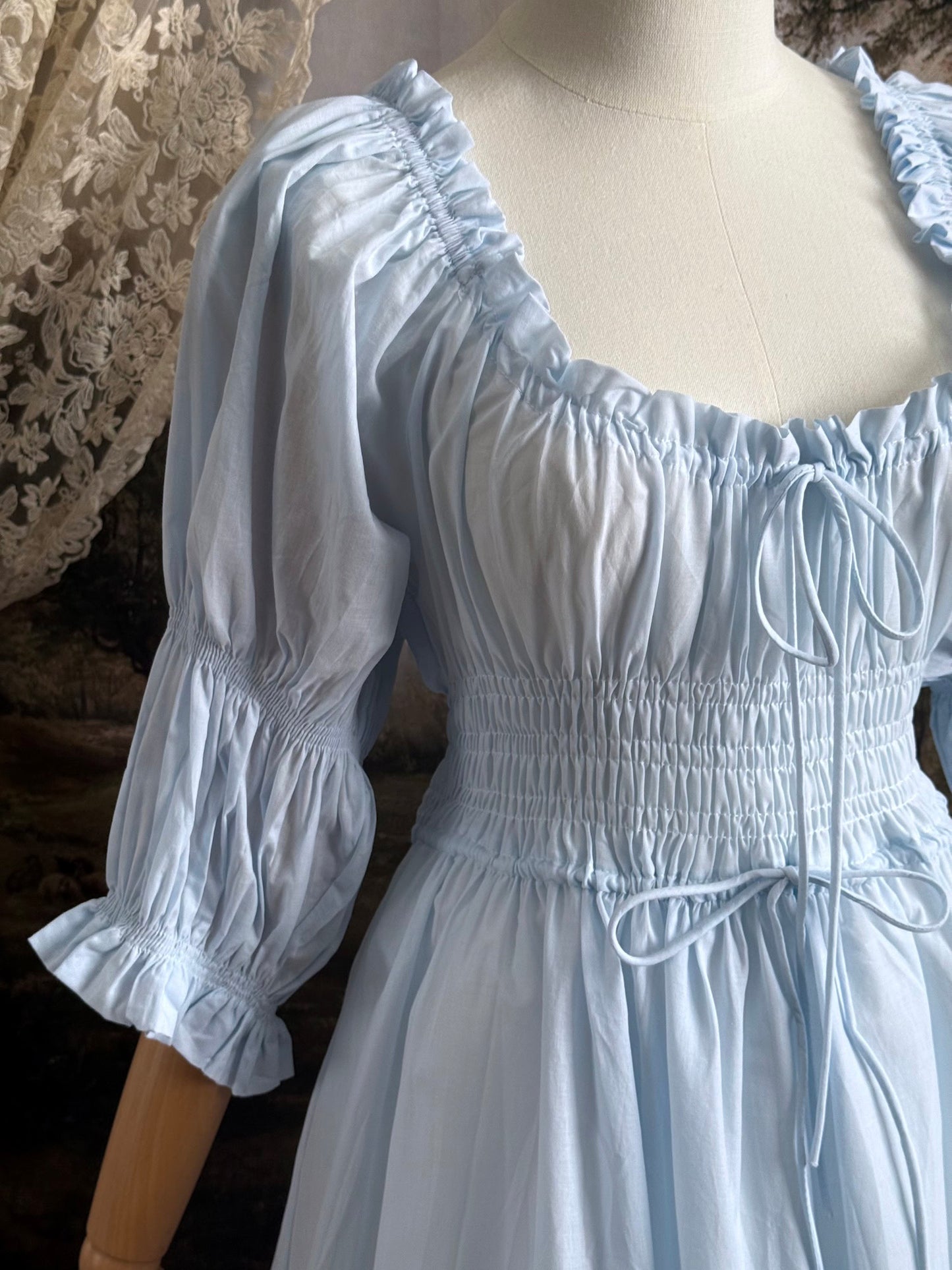 A historically-inspired vintage style light blue shirred / smocked cotton maxi chemise dress with half length virago puff sleeves, pictured on a mannequin