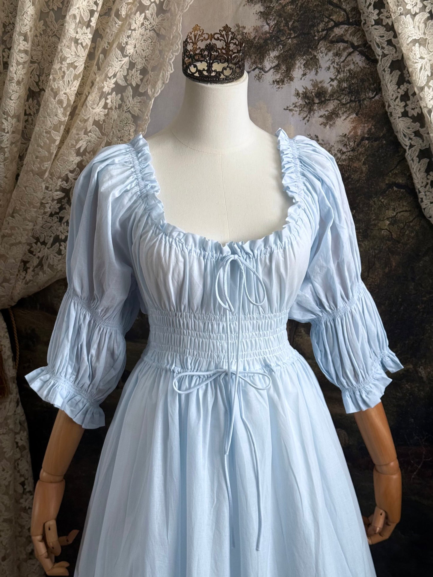 A historically-inspired vintage style light blue shirred / smocked cotton maxi chemise dress with half length virago puff sleeves, pictured on a mannequin