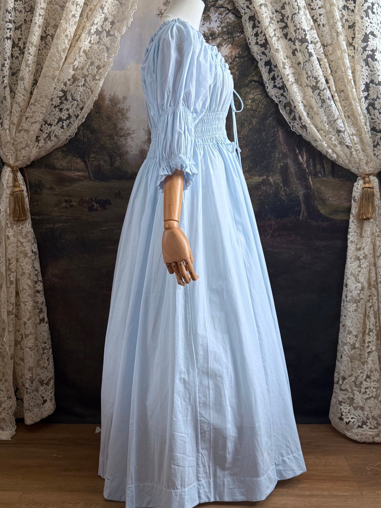 A historically-inspired vintage style light blue shirred / smocked cotton maxi chemise dress with half length virago puff sleeves, pictured on a mannequin