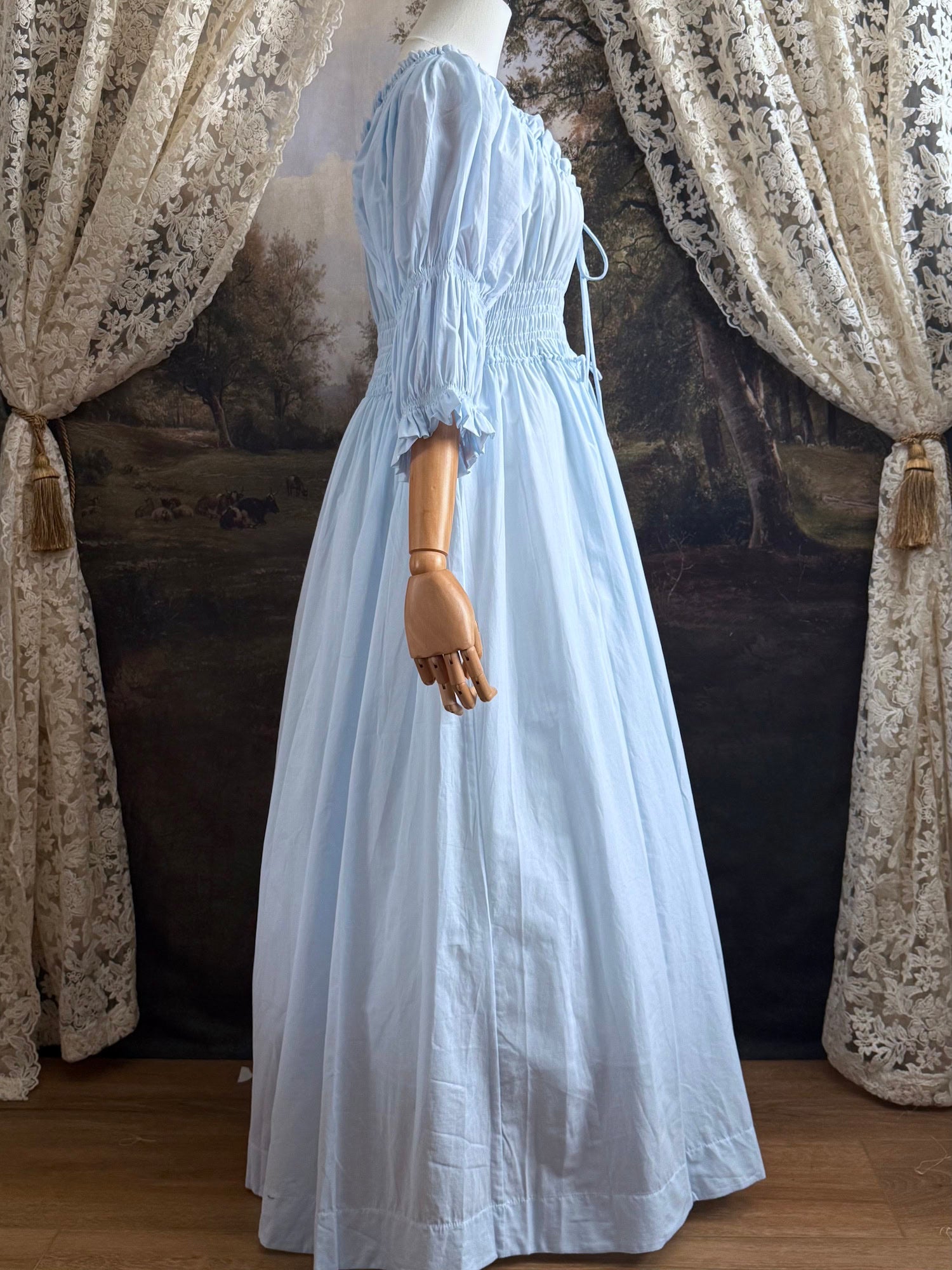 A historically-inspired vintage style light blue shirred / smocked cotton maxi chemise dress with half length virago puff sleeves, pictured on a mannequin