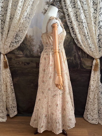 A historically inspired vintage bouquet print floral sleeveless regency rococo style maxi dress with tiered skirt and shirred bodice on a mannequin in front of an art history backdrop