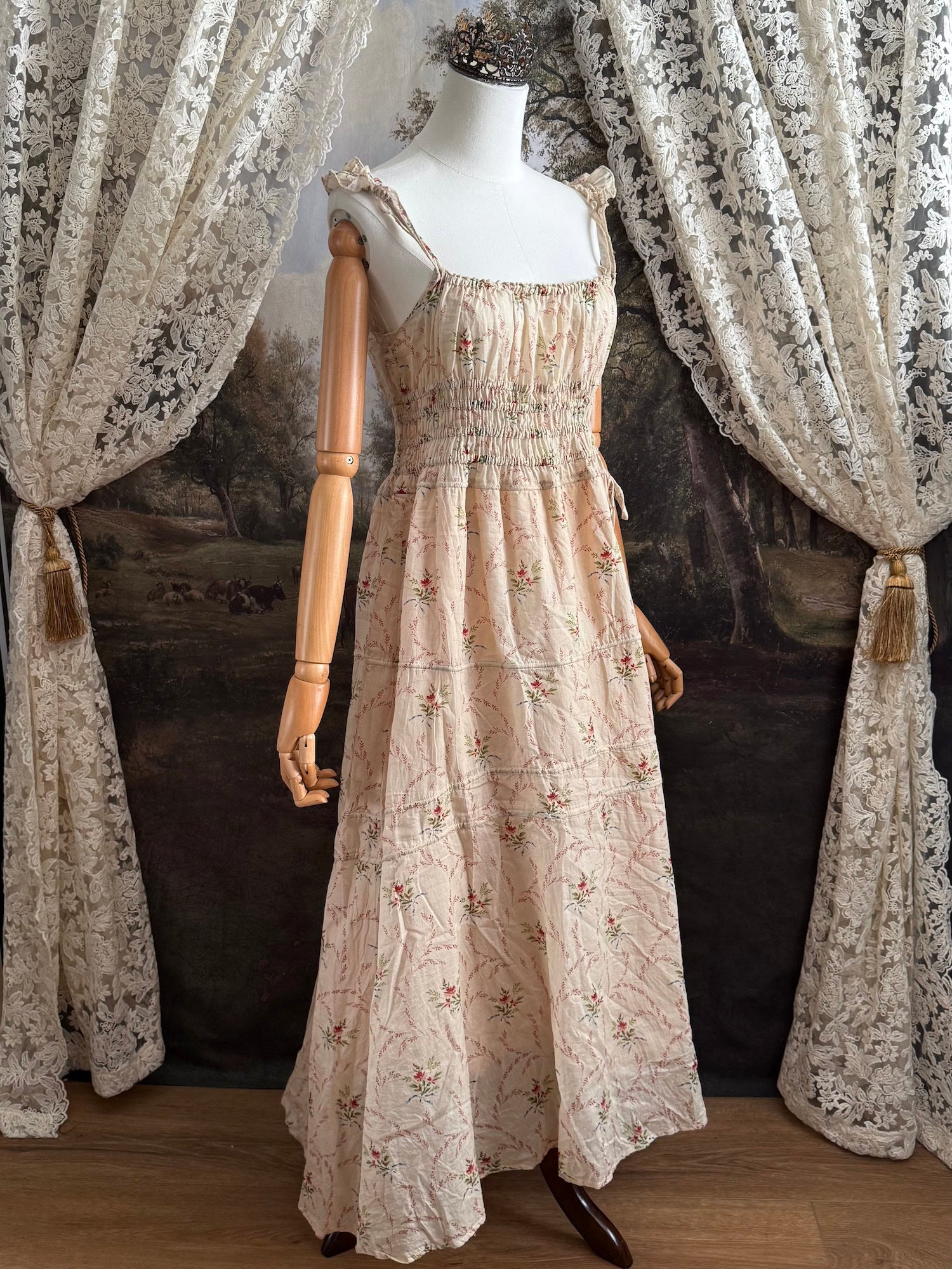 A historically inspired vintage bouquet print floral sleeveless regency rococo style maxi dress with tiered skirt and shirred bodice on a mannequin in front of an art history backdrop