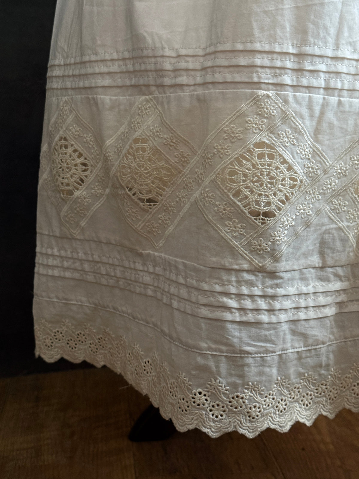 Close up of the folk lace inset into the hem with pintuck details.