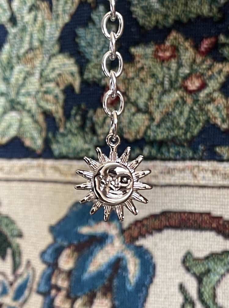 Silver celestial moon and sun charm.