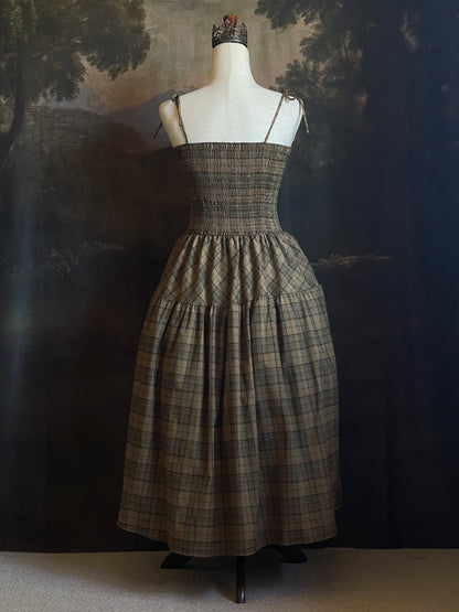 An early medieval era, Celtic historically inspired olive green tartan plaid smocked maxi dress with tiered skirt pictured on a mannequin.