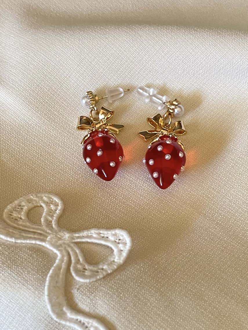 A pair of cottagecore vintage style bow and strawberry earrings in gold metal and red enamel with pearl accents.