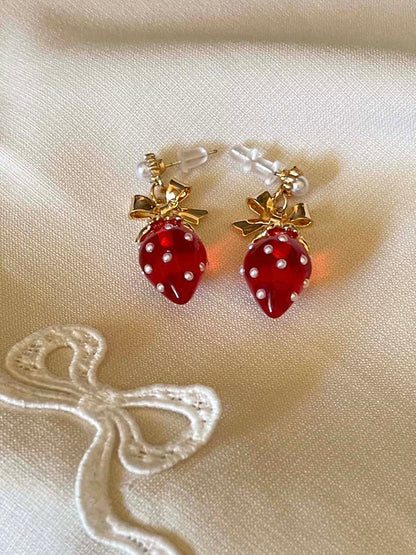 A pair of cottagecore vintage style bow and strawberry earrings in gold metal and red enamel with pearl accents.