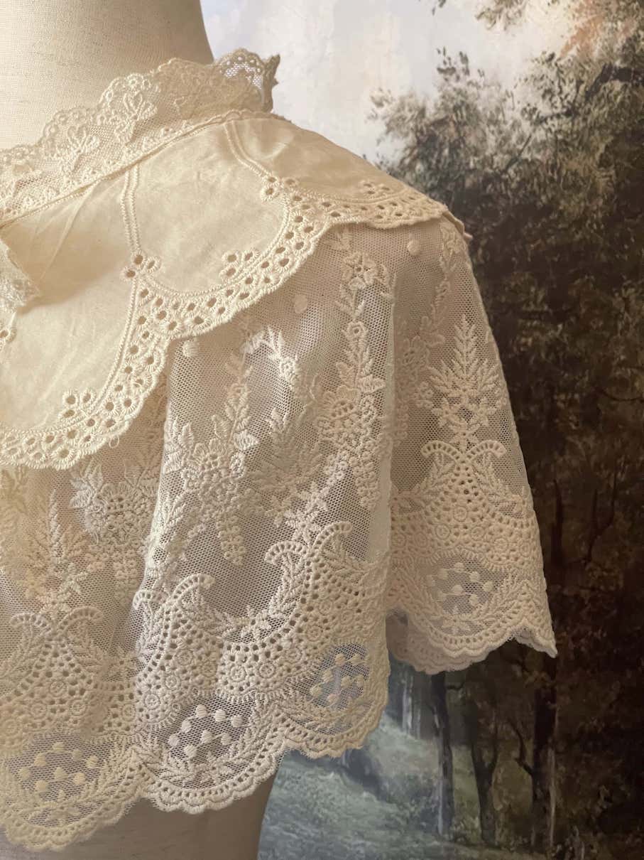 A Historically inspired edwardian victorian regency and rococo style lace capelet shawl in ivory with bow and floral embroidered details.