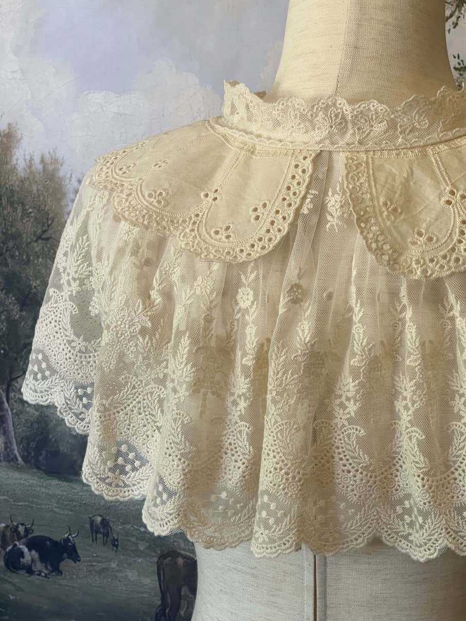 A Historically inspired edwardian victorian regency and rococo style lace capelet shawl in ivory with bow and floral embroidered details.