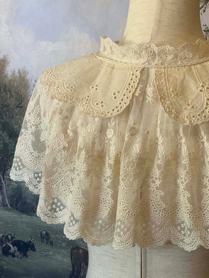 A Historically inspired edwardian victorian regency and rococo style lace capelet shawl in ivory with bow and floral embroidered details.