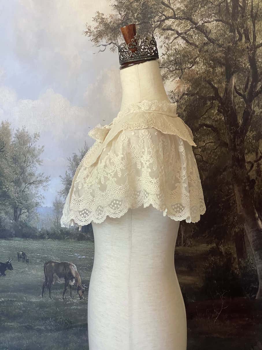 A Historically inspired edwardian victorian regency and rococo style lace capelet shawl in ivory with bow and floral embroidered details.