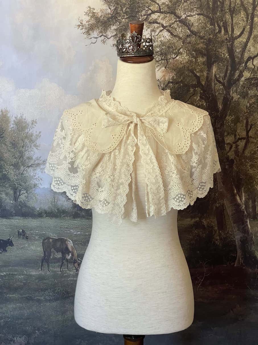 A Historically inspired edwardian victorian regency and rococo style lace capelet shawl in ivory with bow and floral embroidered details.