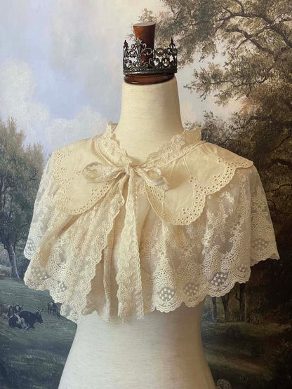 A Historically inspired edwardian victorian regency and rococo style lace capelet shawl in ivory with bow and floral embroidered details.