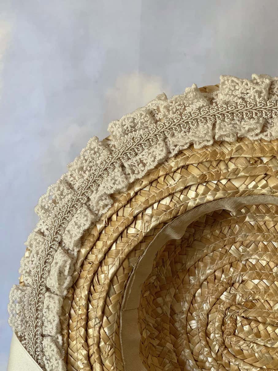 A historically inspired straw bonnet style hat with floral decorations, bow embellishments, ribbons, and lace.  Reminiscent of regency, rococo, victorian, and edwardian eras.