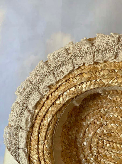 A historically inspired straw bonnet style hat with floral decorations, bow embellishments, ribbons, and lace.  Reminiscent of regency, rococo, victorian, and edwardian eras.
