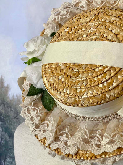 A historically inspired straw bonnet style hat with floral decorations, bow embellishments, ribbons, and lace.  Reminiscent of regency, rococo, victorian, and edwardian eras.
