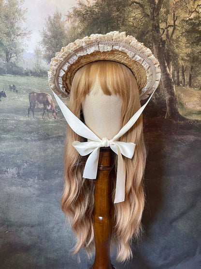 A historically inspired straw bonnet style hat with floral decorations, bow embellishments, ribbons, and lace.  Reminiscent of regency, rococo, victorian, and edwardian eras.