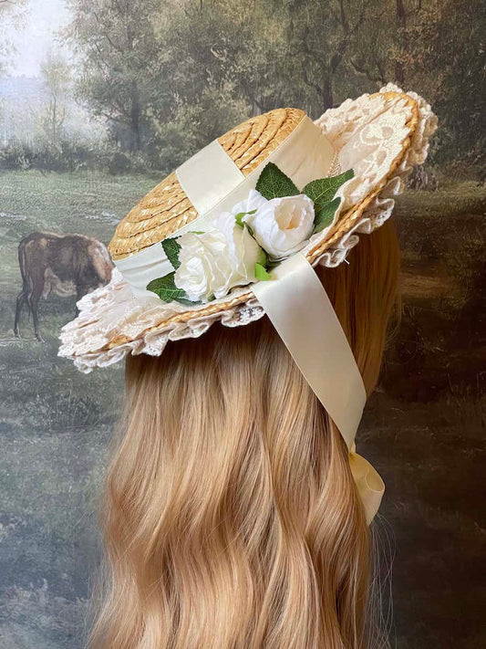 A historically inspired straw bonnet style hat with floral decorations, bow embellishments, ribbons, and lace.  Reminiscent of regency, rococo, victorian, and edwardian eras.