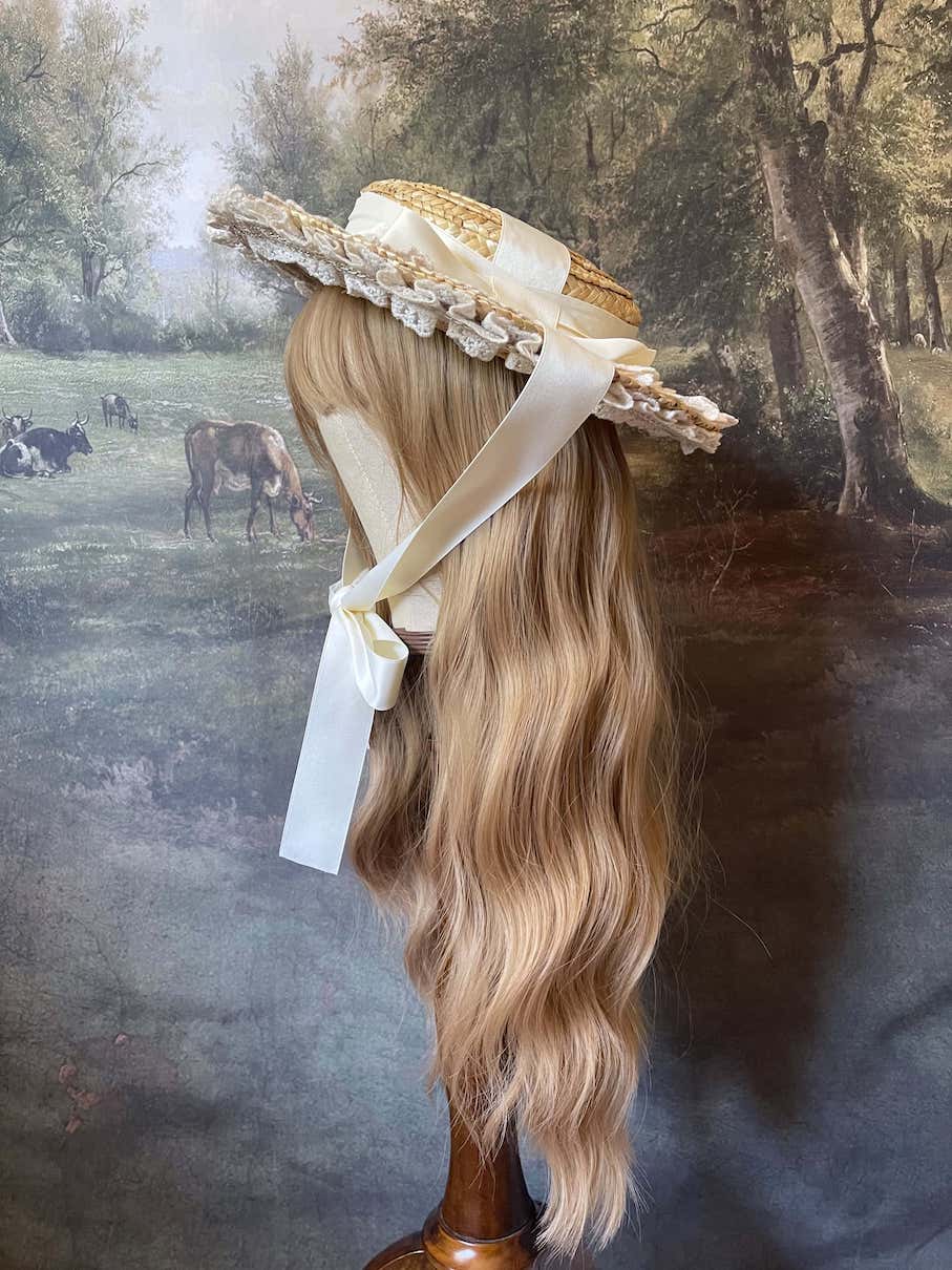 A historically inspired straw bonnet style hat with floral decorations, bow embellishments, ribbons, and lace.  Reminiscent of regency, rococo, victorian, and edwardian eras.