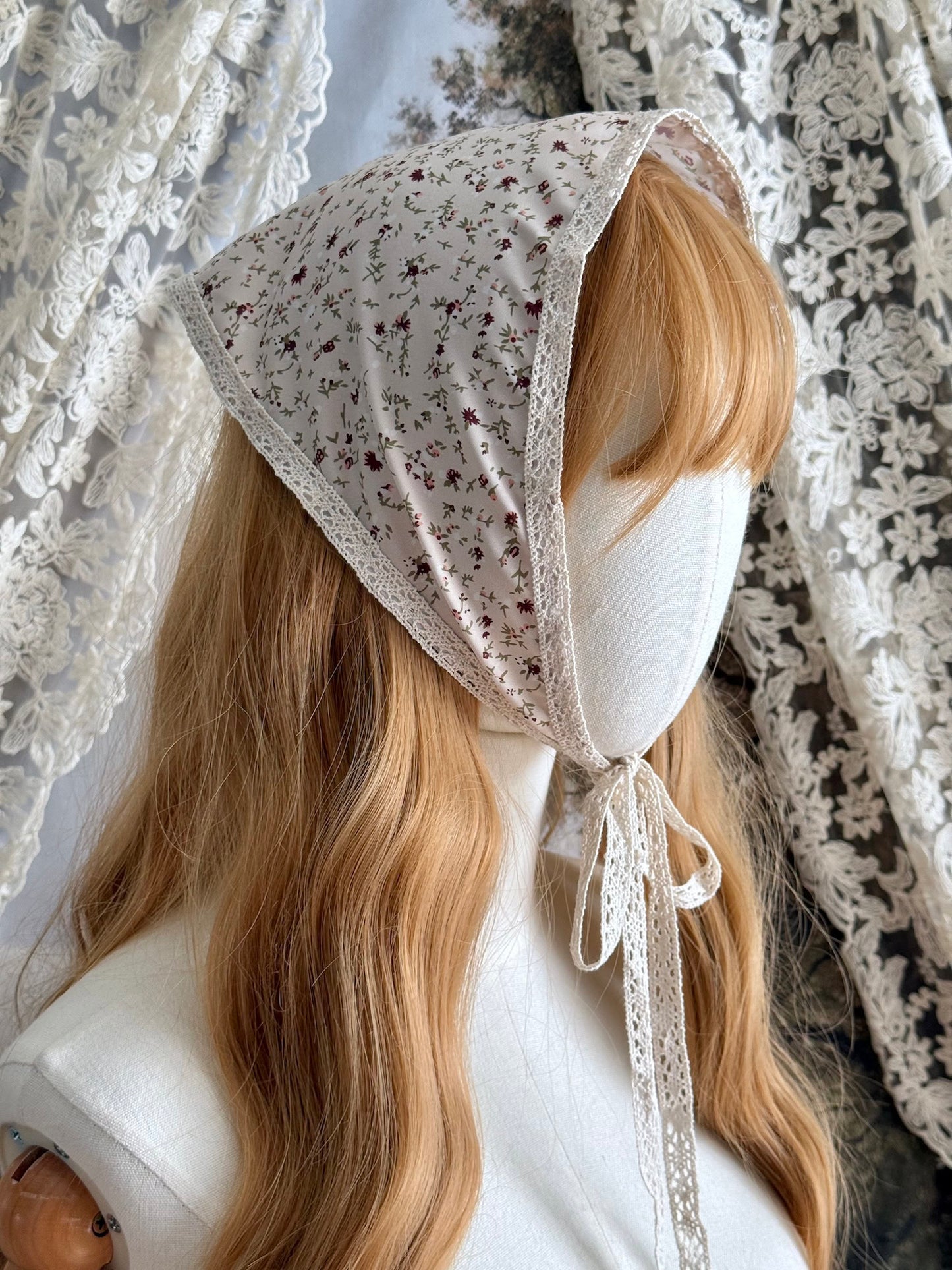A Vintage inspired Cream & Pink Floral Print Babushka Triangle Headdress with lace trim on a mannequin head