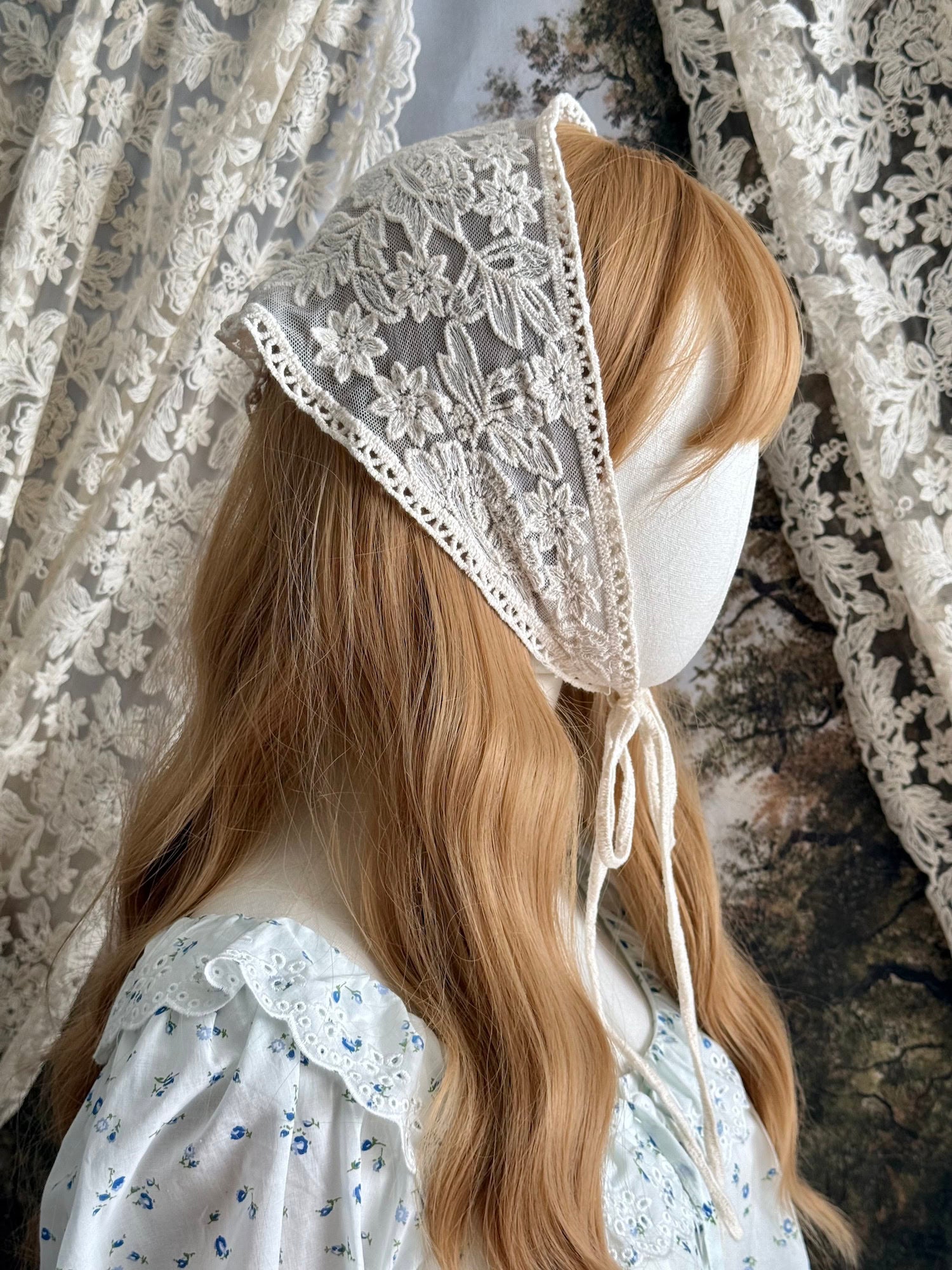 A vintage inspired ivory / cream floral embroidered lace triangle headdress babushka bonnet on a mannequin head