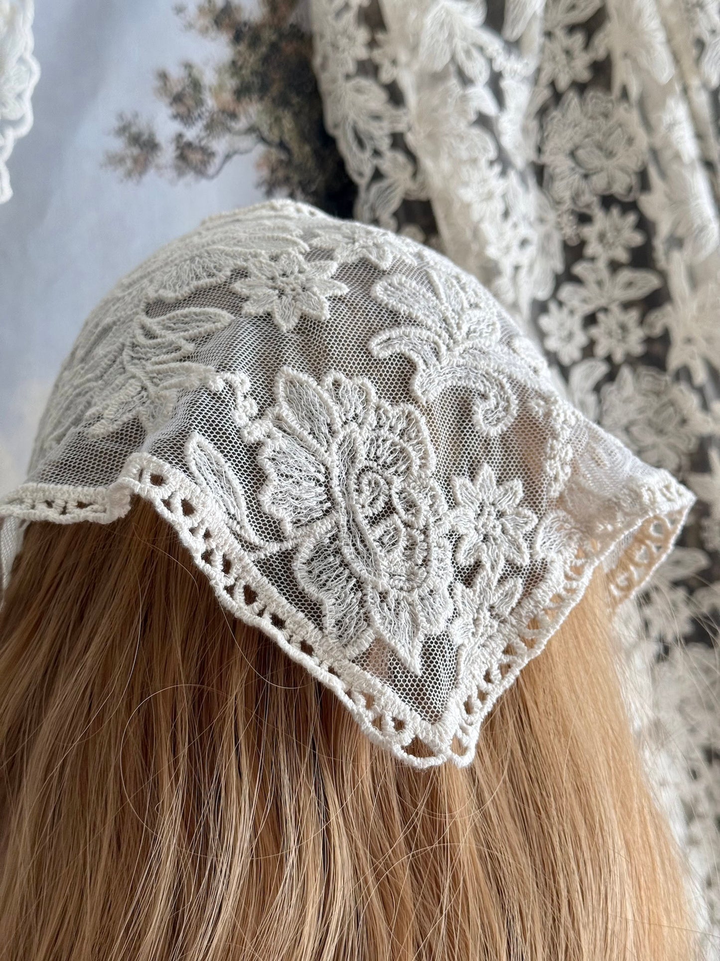 A vintage inspired ivory / cream floral embroidered lace triangle headdress babushka bonnet on a mannequin head