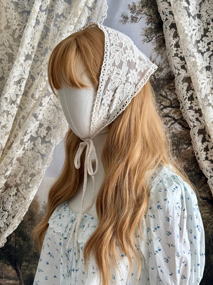 A vintage inspired ivory / cream floral embroidered lace triangle headdress babushka bonnet on a mannequin head