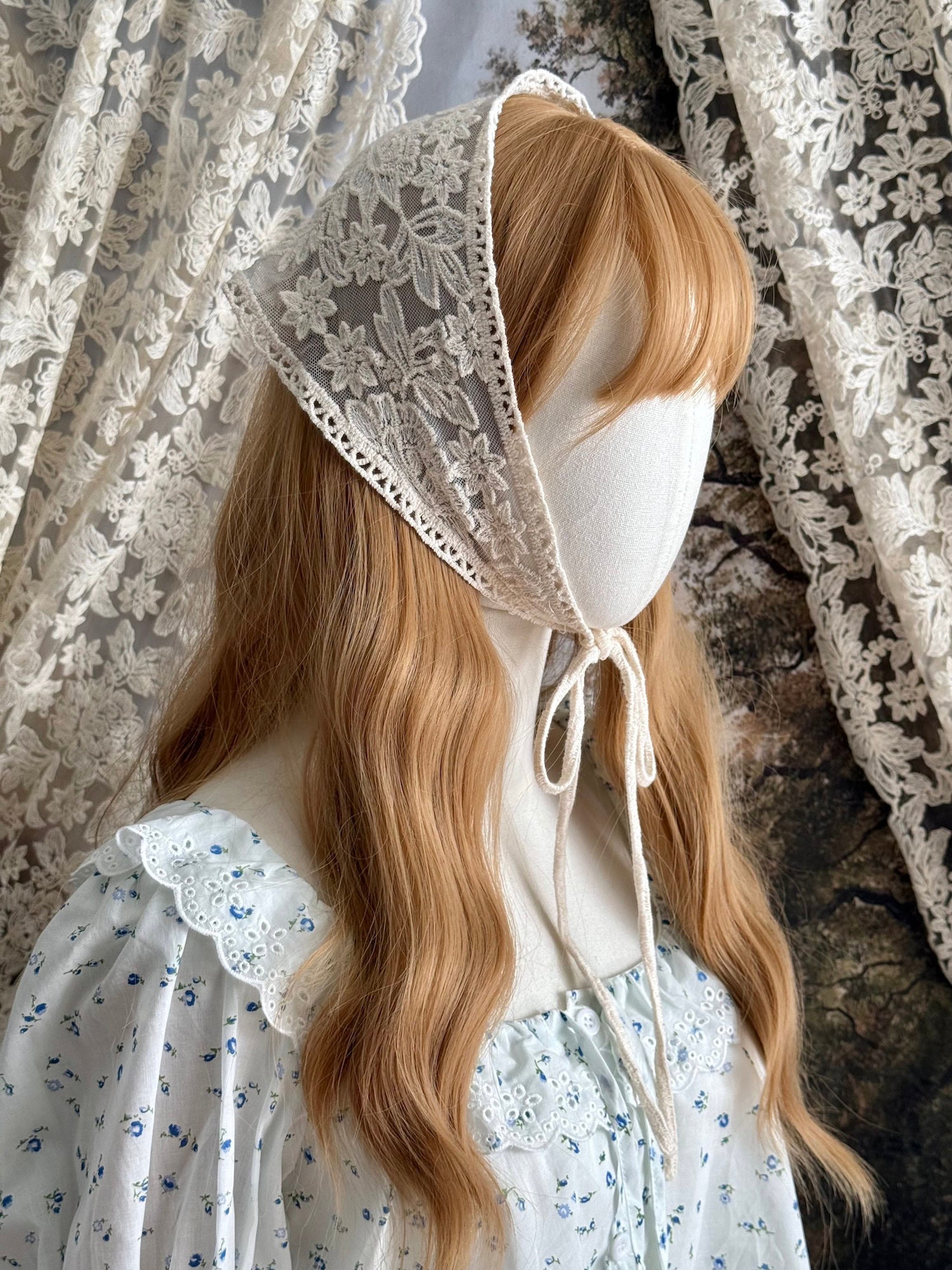 A vintage inspired ivory / cream floral embroidered lace triangle headdress babushka bonnet on a mannequin head