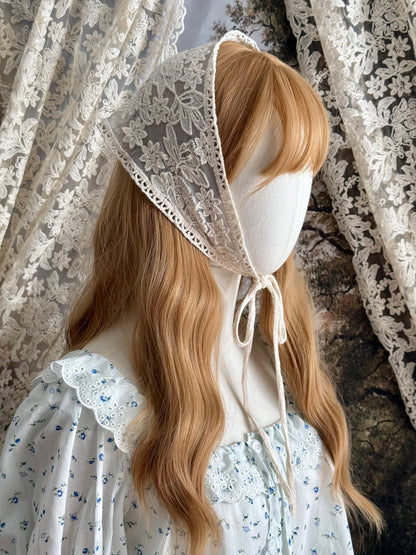 A vintage inspired ivory / cream floral embroidered lace triangle headdress babushka bonnet on a mannequin head