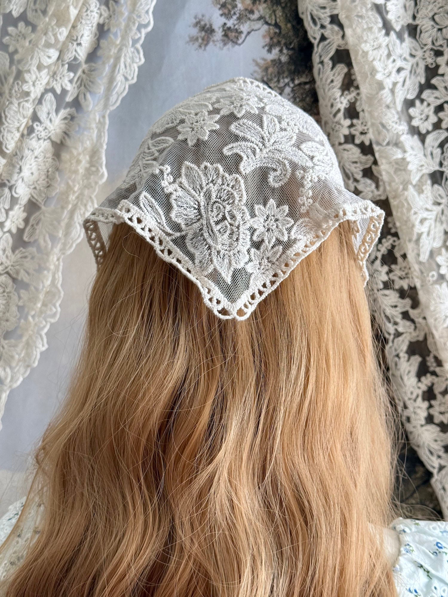 A vintage inspired ivory / cream floral embroidered lace triangle headdress babushka bonnet on a mannequin head