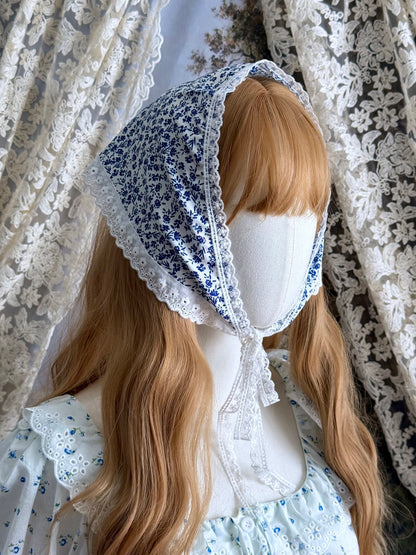 A vintage style historically inspired blue and white floral print babushka triangle headdress with floral lace trim pictured on a mannequin.