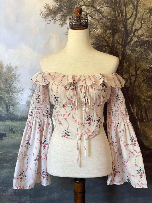 A historically inspired off-shoulder ruffle neckline floral print blouse with bell sleeves and a structured corset-like bodice.