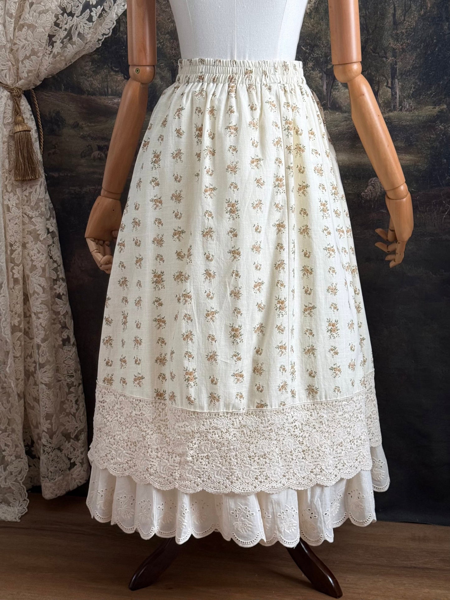 A historically inspired victorian style Ivory cotton floral printed maxi skirt with scalloped lace trim on a mannequin in front of an art history backdrop