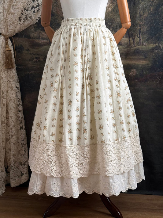 A historically inspired victorian style Ivory cotton floral printed maxi skirt with scalloped lace trim on a mannequin in front of an art history backdrop
