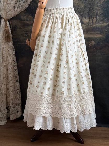 A historically inspired victorian style Ivory cotton floral printed maxi skirt with scalloped lace trim on a mannequin in front of an art history backdrop