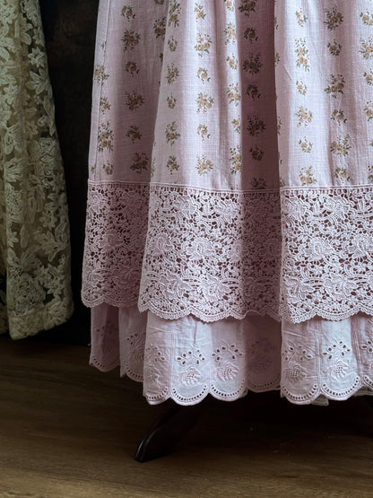 A vintage style historical fashion inspire floral print cotton skirt in mauve with scalloped floral lace trim, pictured on a mannequin in front of a historical painting backdrop.