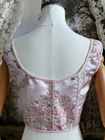 Historical fashion inspired baroque to rococo era front-laced corset stays top in pastel pink floral jacquard fabric, pictured on a mannequin.