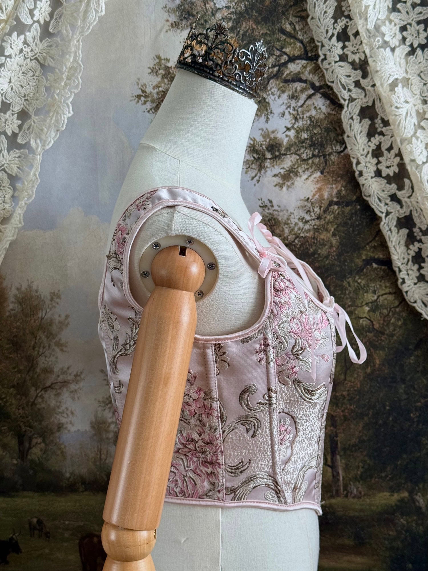 Historical fashion inspired baroque to rococo era front-laced corset stays top in pastel pink floral jacquard fabric, pictured on a mannequin.