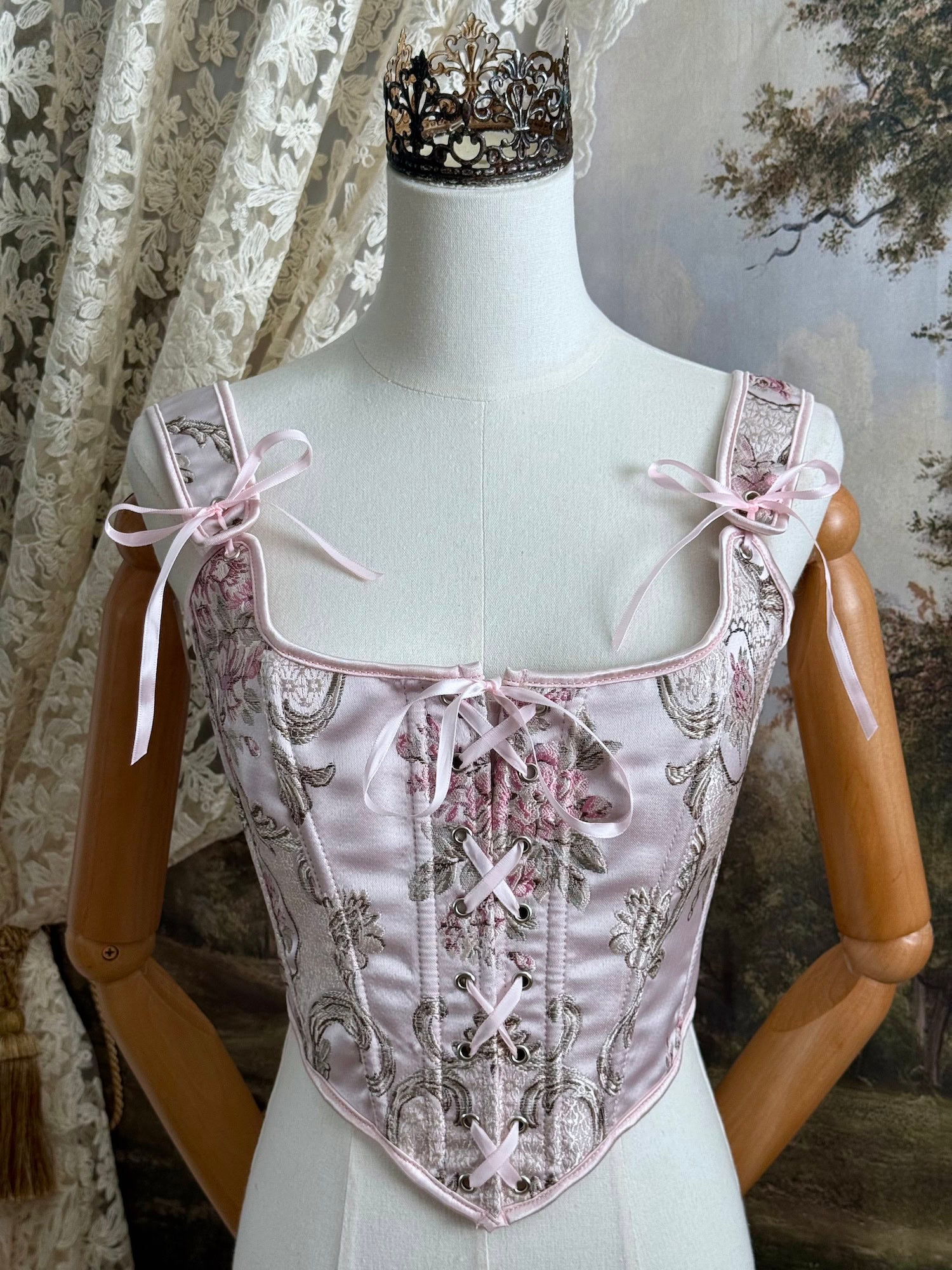 Historical fashion inspired baroque to rococo era front-laced corset stays top in pastel pink floral jacquard fabric, pictured on a mannequin.